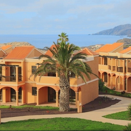 un grupo de edificios con techos naranjas y palmeras frente al océano