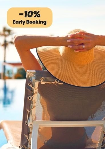 a woman wearing a hat is sitting in a chair near a pool .