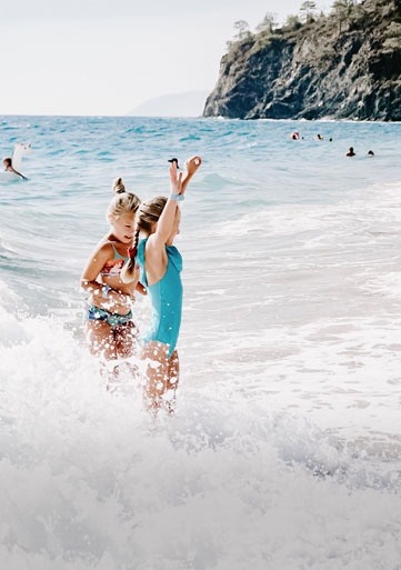 dos niñas están jugando en el océano en la playa .
