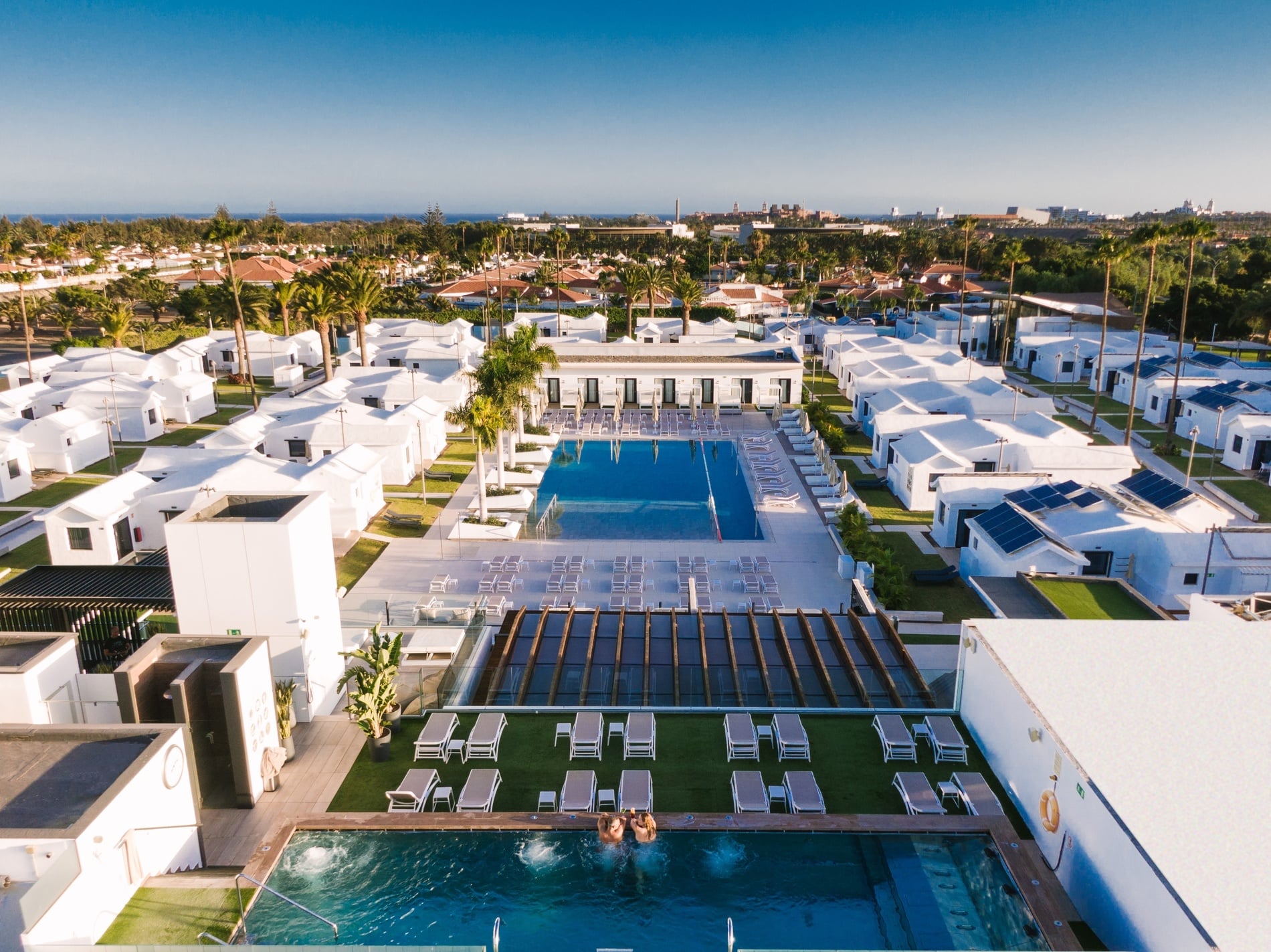 un hombre y una mujer caminan por una piscina en un resort