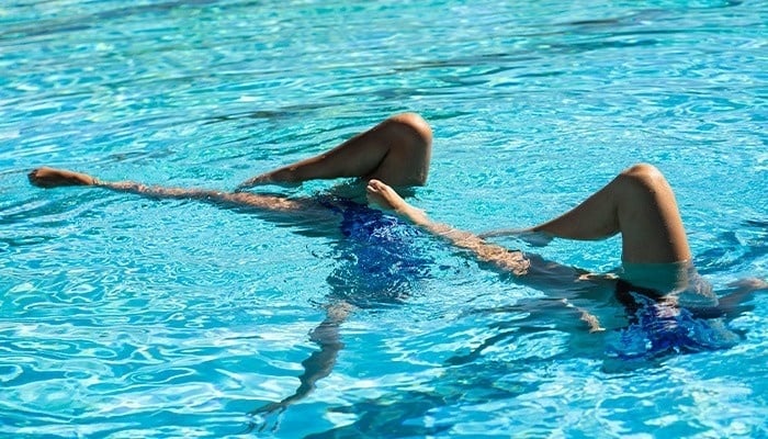una mujer flota en la superficie de una piscina con las piernas cruzadas