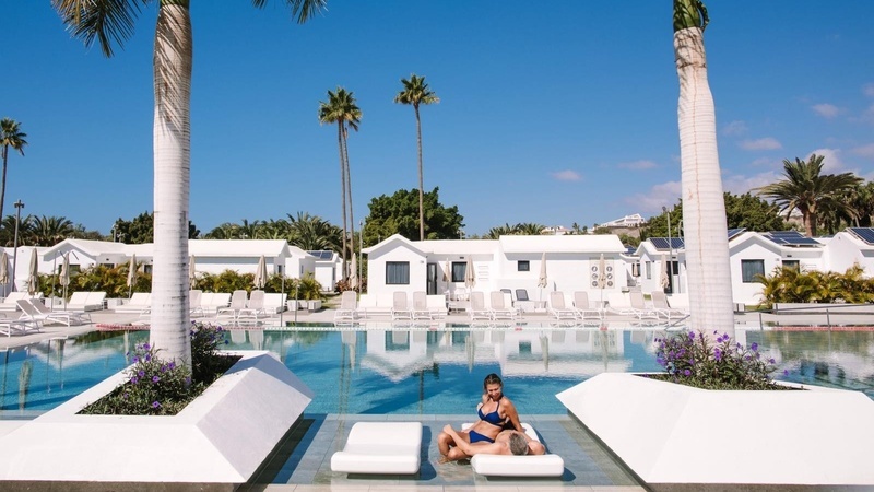 Club Maspalomas luxury pool with palm trees and sun loungers.