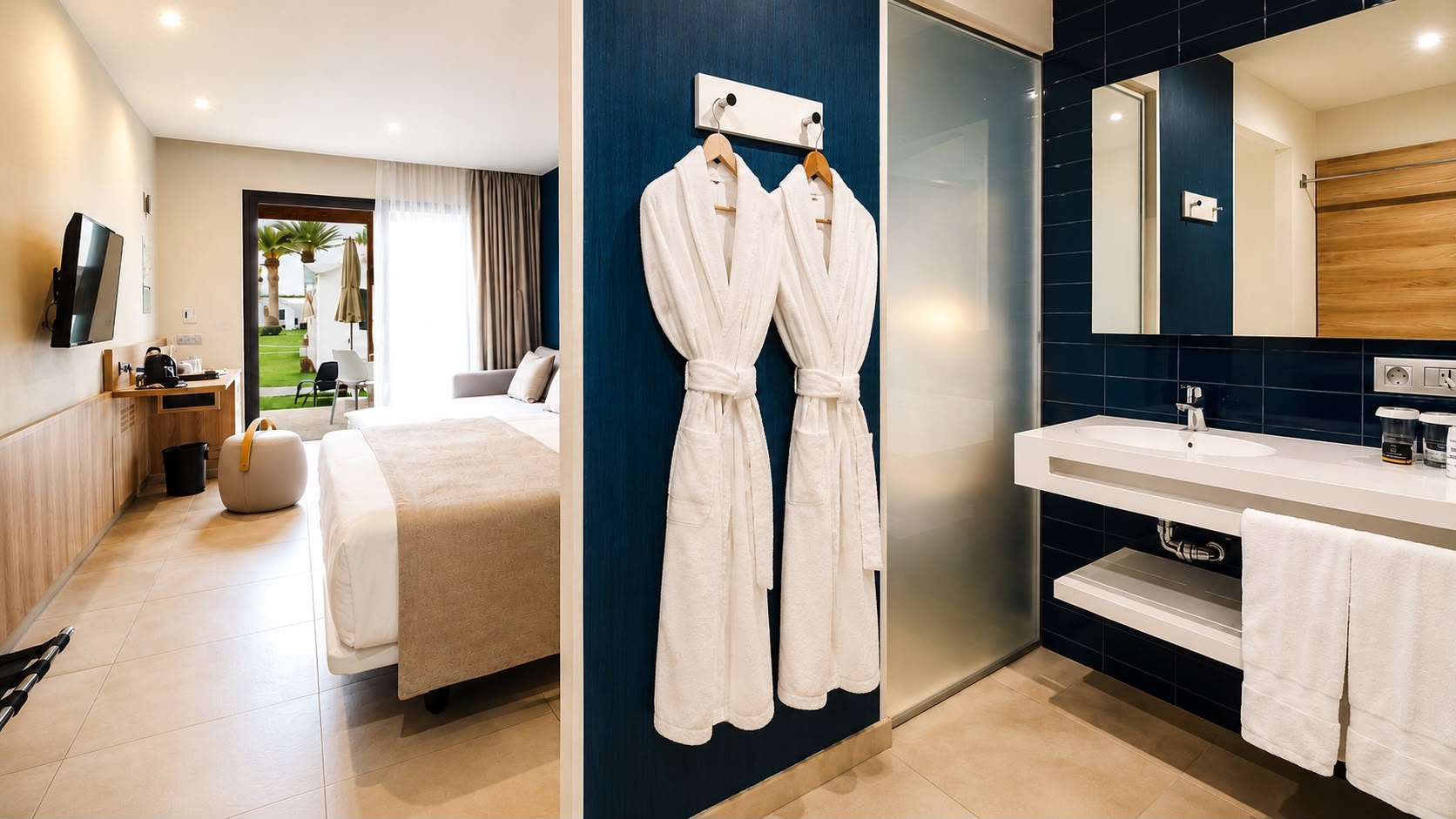 Modern hotel room and bathroom at Club Maspalomas with a bed, sink, and view of the garden.