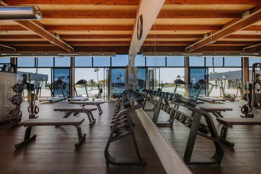 un gimnasio lleno de equipos y grandes ventanas