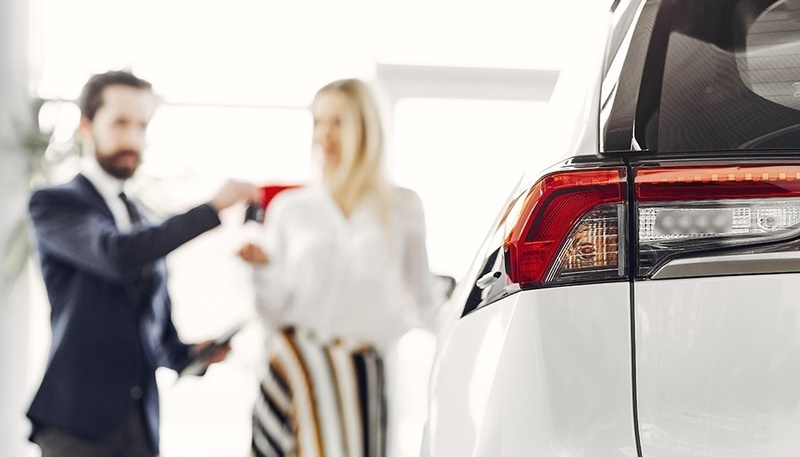 a man and woman are looking at a car in a showroom