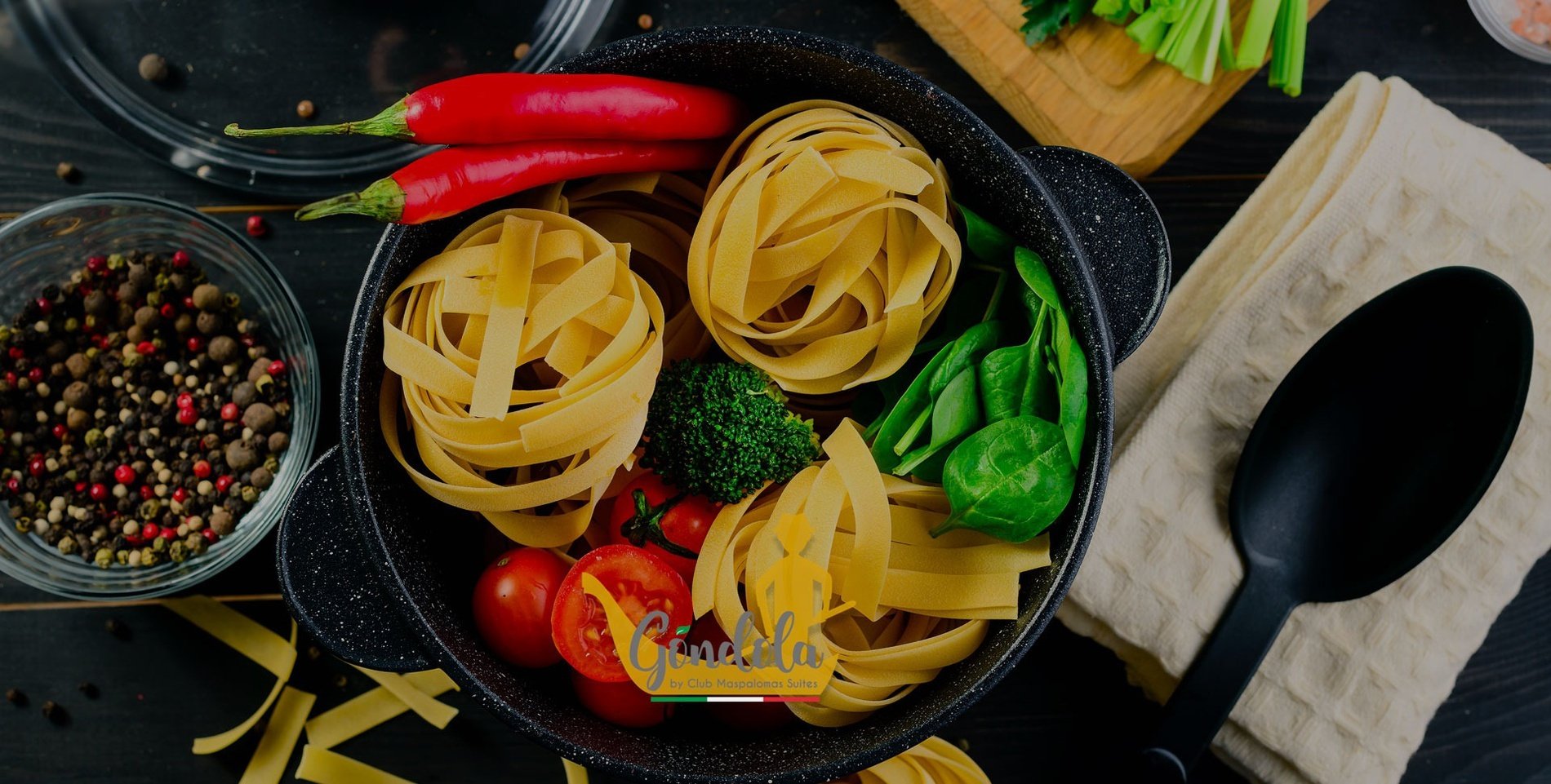 una olla llena de pasta y verduras junto a una cuchara negra