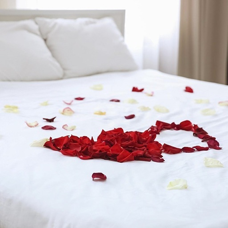 ein Bett mit einem Herz aus Rosenblättern bedeckt