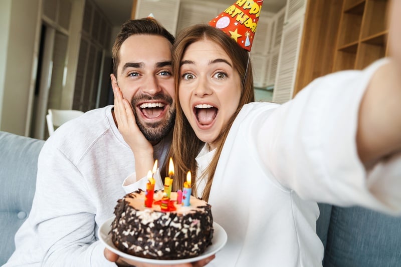 un hombre y una mujer toman un selfie con un pastel de cumpleaños