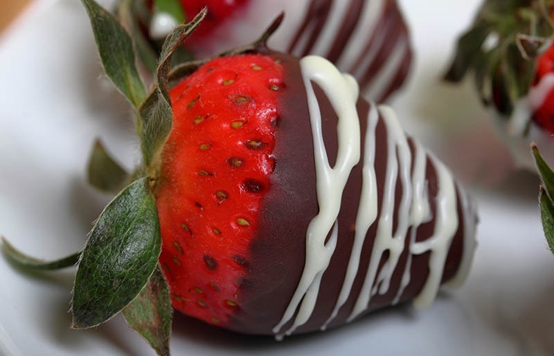 un primer plano de una fresa cubierta de chocolate en un plato