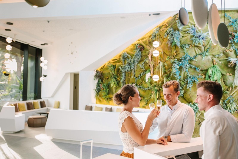 Moderne Rezeption Club Maspalomas mit grüner Wand und weißen Sitzmöbeln.