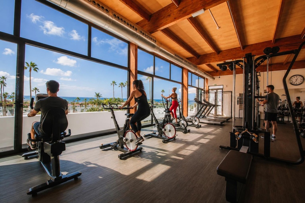 Moderne fitnessruimte in Club Maspalomas met uitzicht op de zonsondergang.