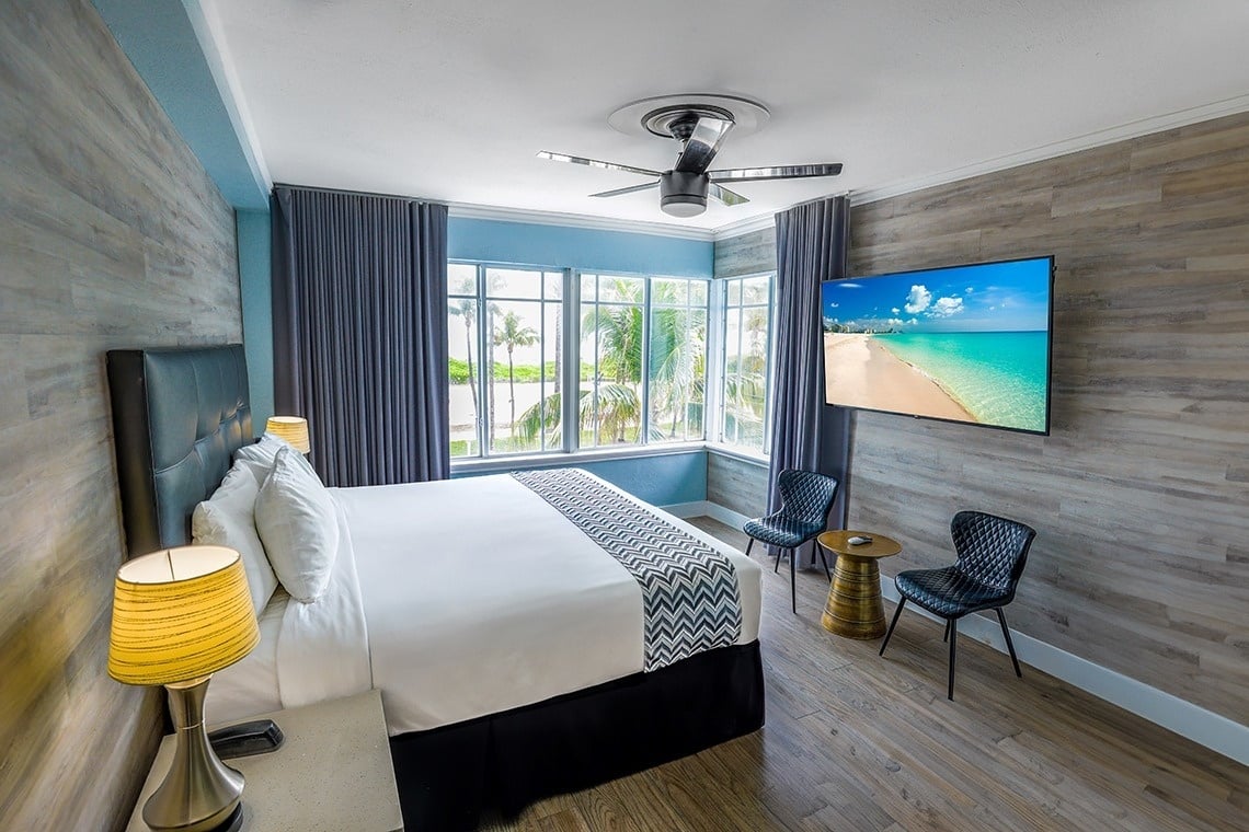 una habitación de hotel con una cama y una televisión que muestra una playa
