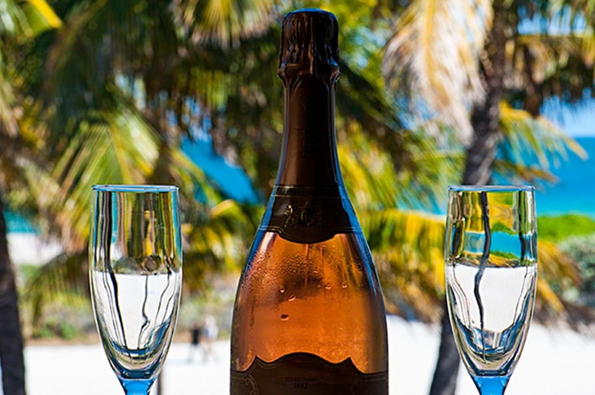a woman is sitting on the edge of a swimming pool holding a glass of champagne .