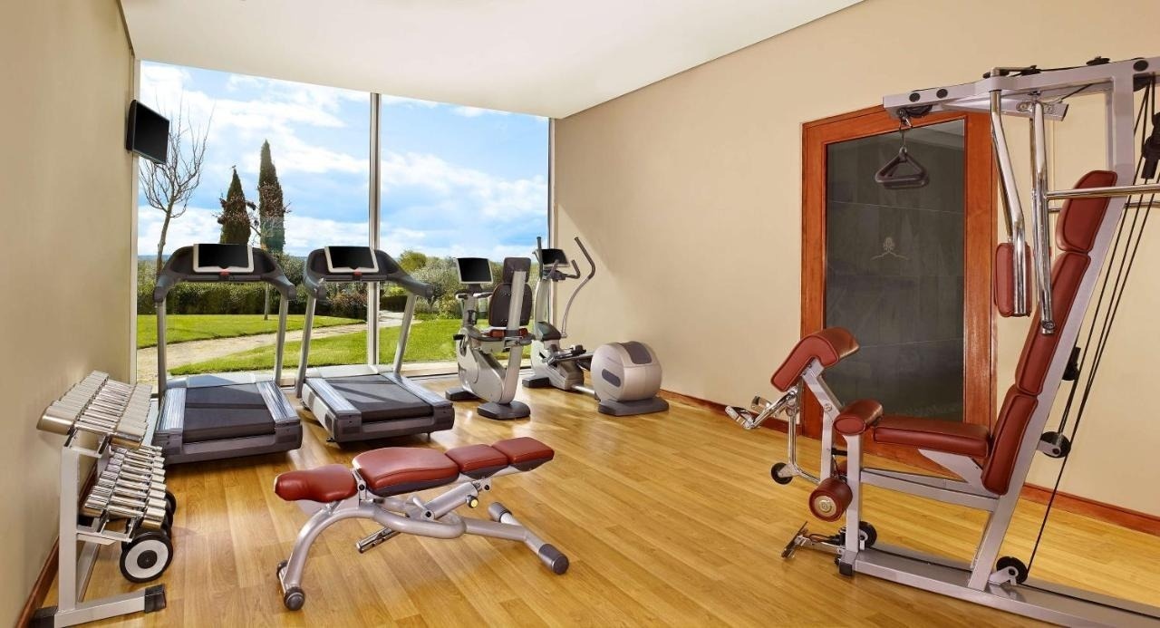 Modern gym at Convento do Espinheiro with treadmills, machines, and weights.