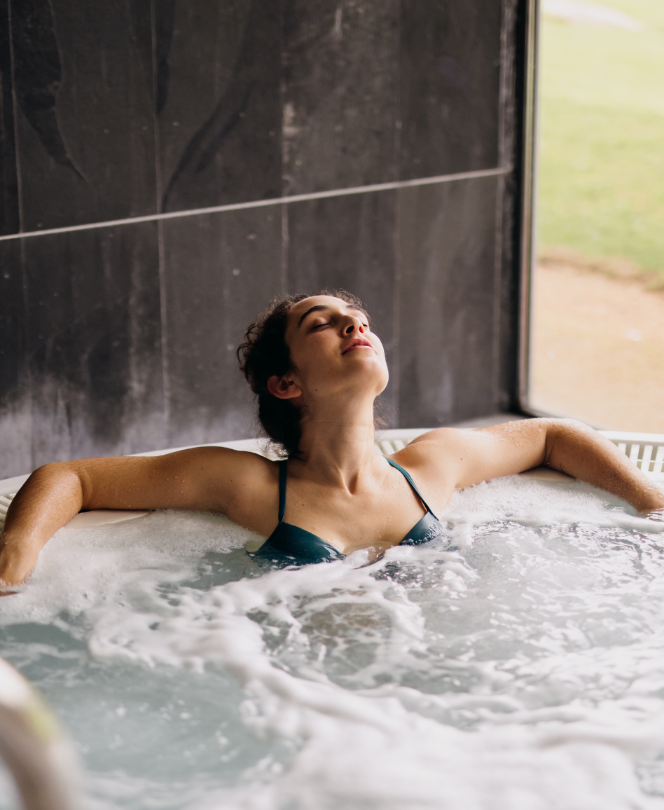 uma mulher está deitada em uma banheira de hidromassagem com os olhos fechados