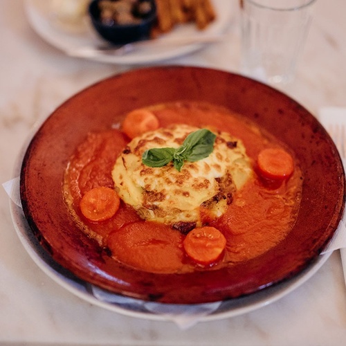 un plato de lasagna con tomates y albahaca encima