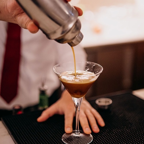 un barman prepara un cóctel en una copa de martini
