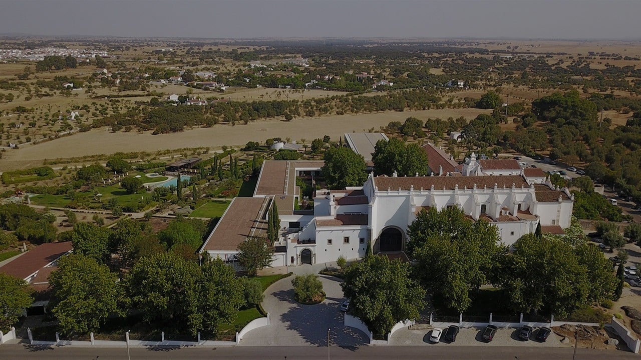 an aerial view of a large white building surrounded by trees