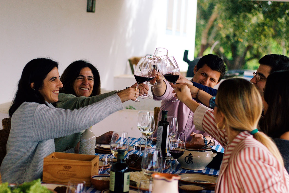 Convento do Espinheiro guests enjoy wine toast at a picturesque outdoor table.