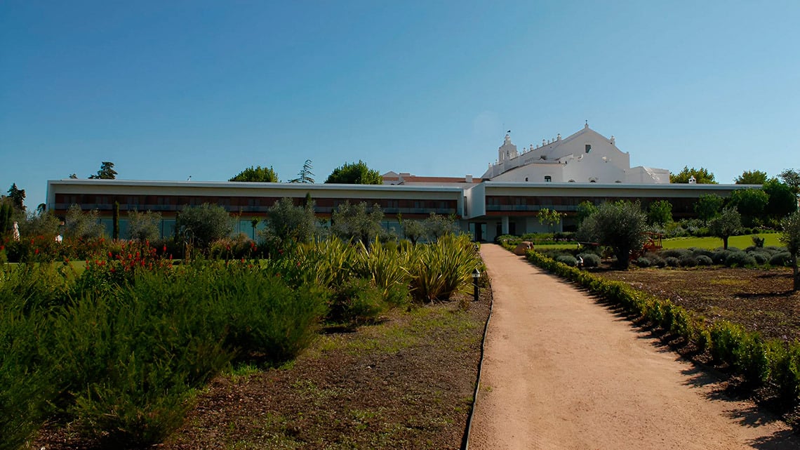 Convento do Espinheiro: paisagem com jardins, edifício contemporâneo e arquitetura branca.