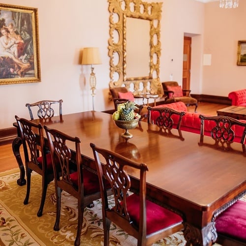 una mesa de comedor con sillas rojas y un jarrón de frutas encima