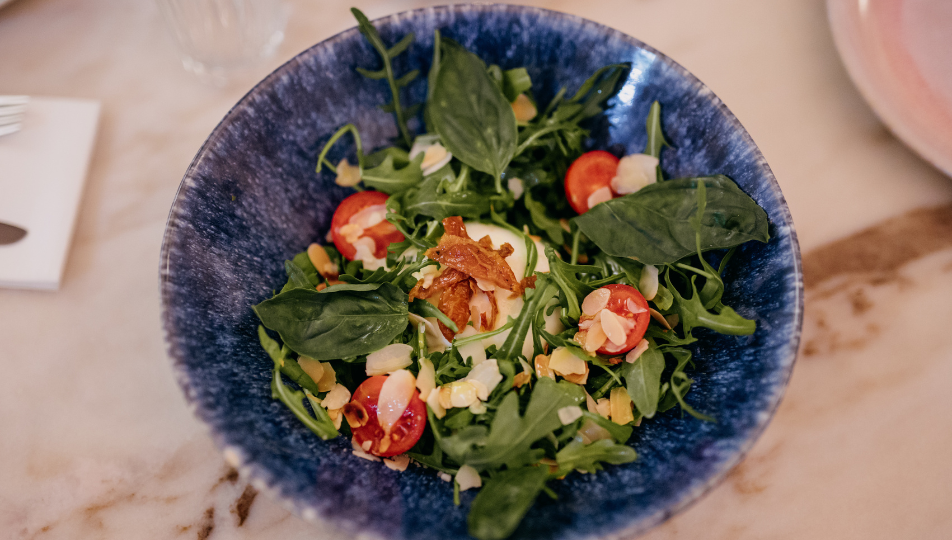 a person holding a plate of food on a table