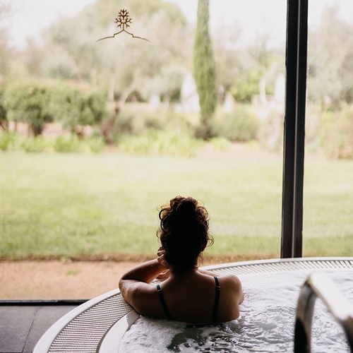 una mujer se sienta en una bañera de hidromasaje y mira por la ventana