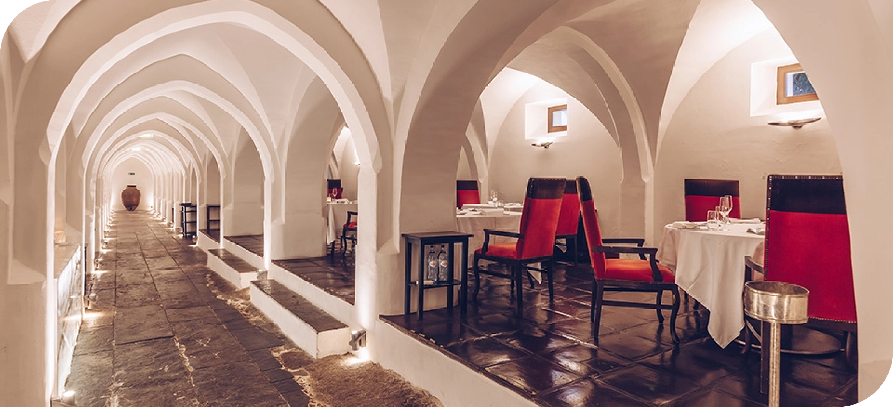 a long hallway with arches and tables and chairs