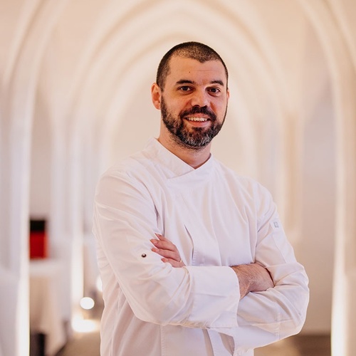 un chef con los brazos cruzados sonríe para la cámara