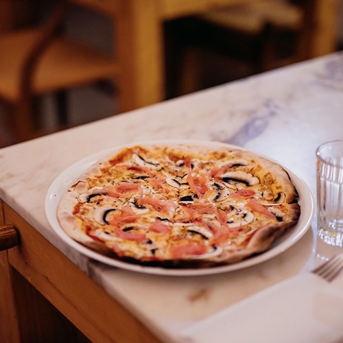 una pizza con champiñones y jamón está sobre una mesa
