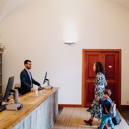 una mujer y un niño caminan hacia el mostrador de un hotel