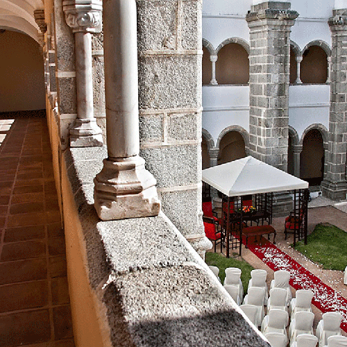 una fila de sillas blancas están alineadas en un patio con una alfombra roja