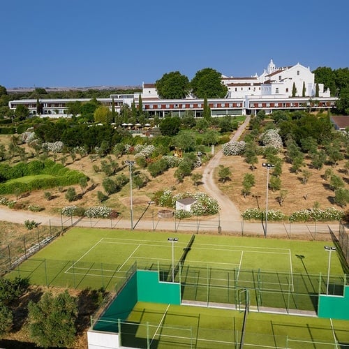 una vista aérea de un campo de tenis con un edificio blanco en el fondo