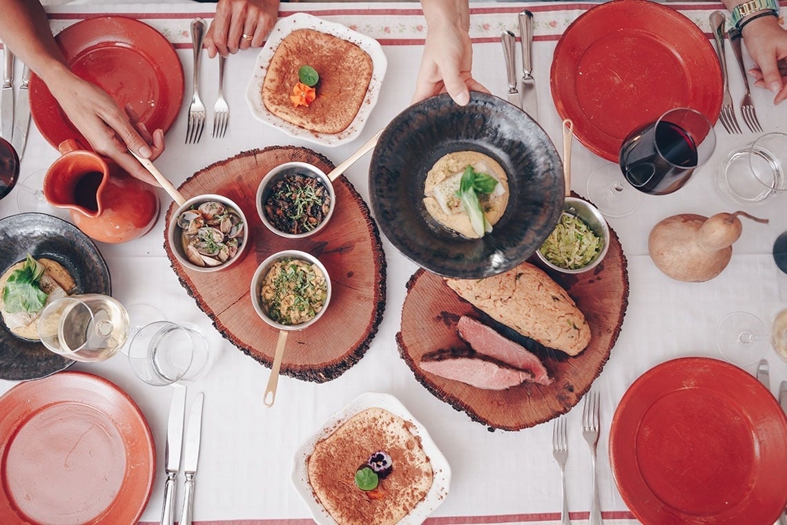 a person holding a plate of food on a table
