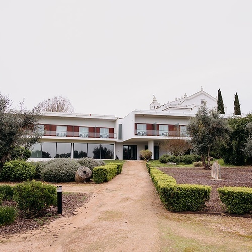 un gran edificio blanco rodeado de árboles y arbustos