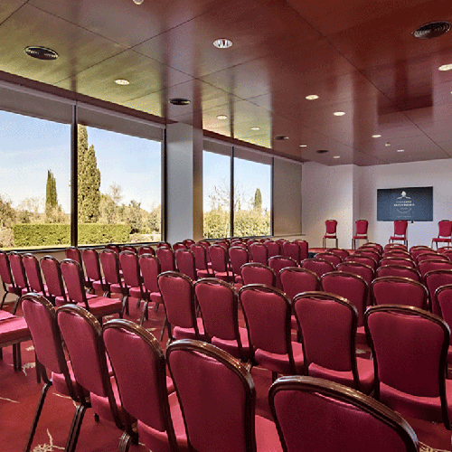 una sala de conferencias llena de sillas rojas y una pantalla