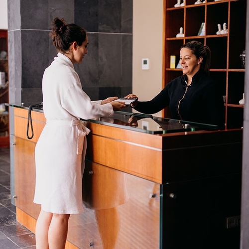 una mujer en bata de baño recibe una visita en la recepción de un spa