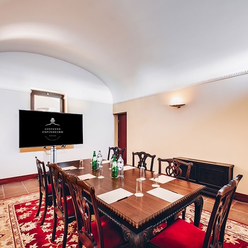 una sala de conferencias con una mesa de madera y sillas