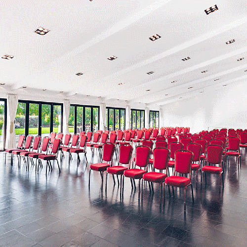 una sala de conferencias llena de sillas rojas y ventanas