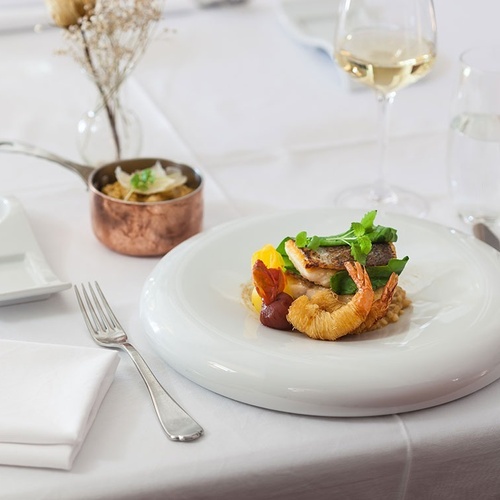 un plato de comida está sobre una mesa junto a una copa de vino