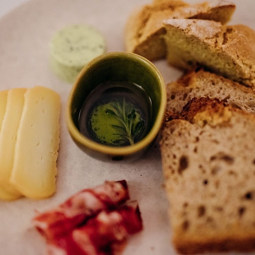 un plato de queso y pan con un tazón de aceite