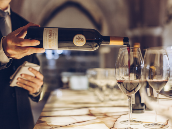 a bottle of wine with a tree on it is being poured into two wine glasses