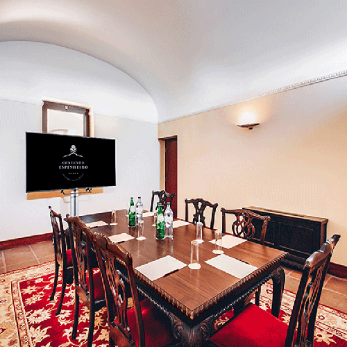 una sala de conferencias con una mesa y sillas y una pantalla que dice hotel imperial