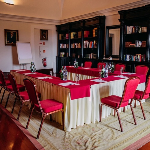 una sala de conferencias con una mesa y sillas rojas