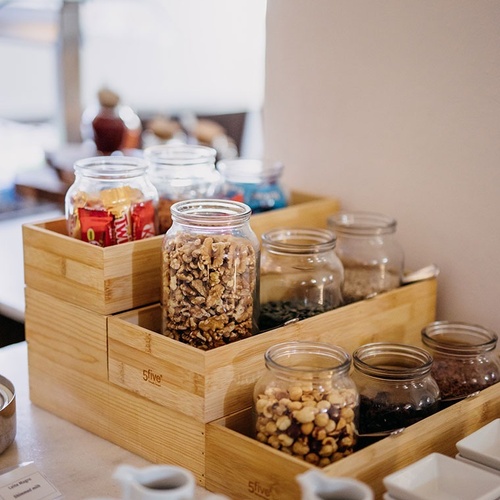 una bandeja de madera con tarros de comida y tazas de café