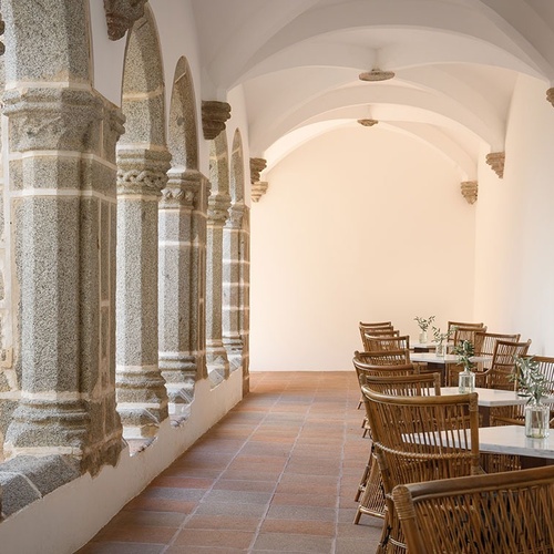 un pasillo con columnas de granito y mesas y sillas de mimbre