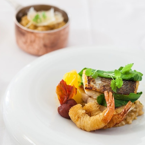 un plato de comida con camarones y verduras en una mesa