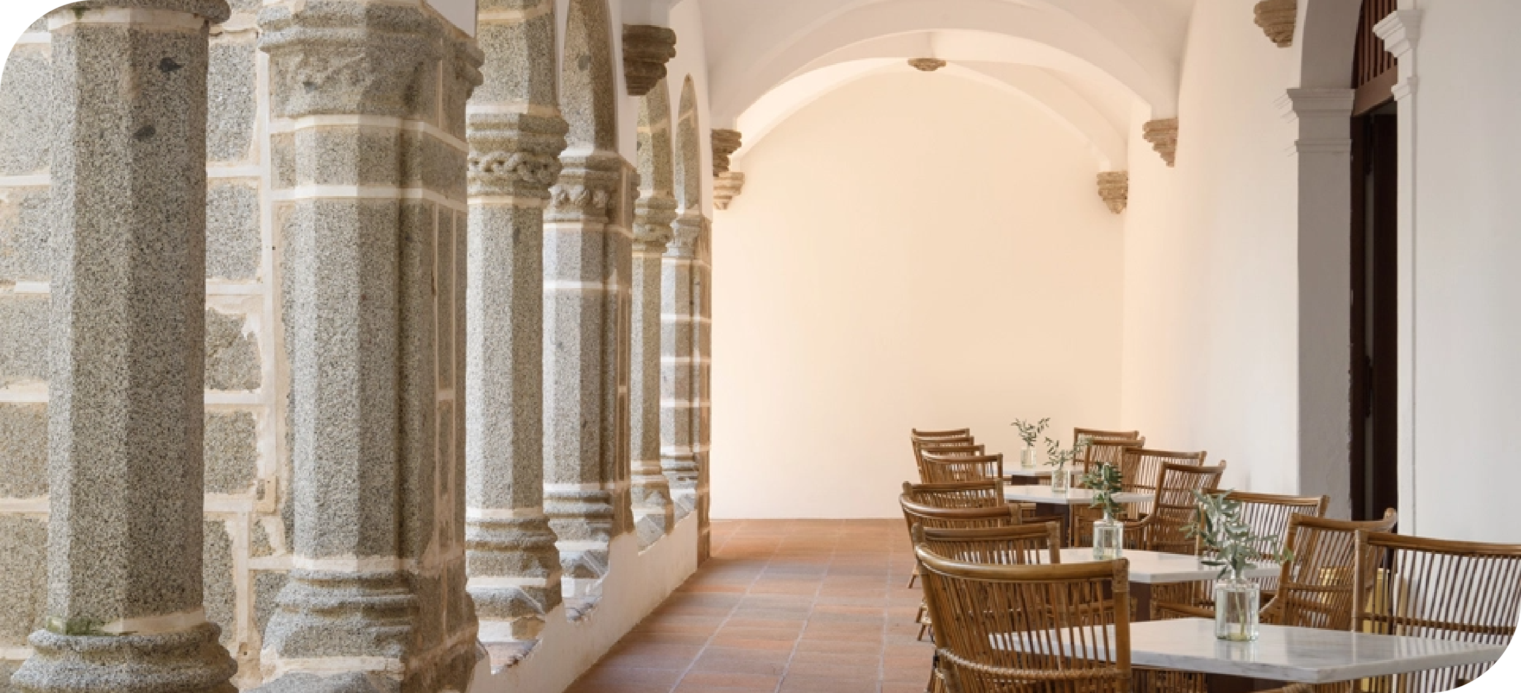 a long hallway with columns and tables and chairs