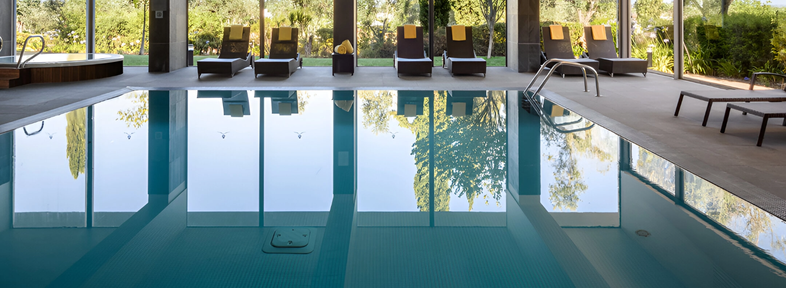 uma grande piscina com cadeiras e jacuzzi ao fundo