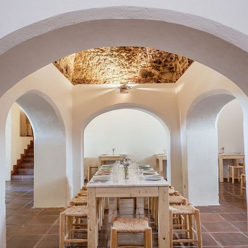 una larga mesa de madera con platos y vasos sobre ella